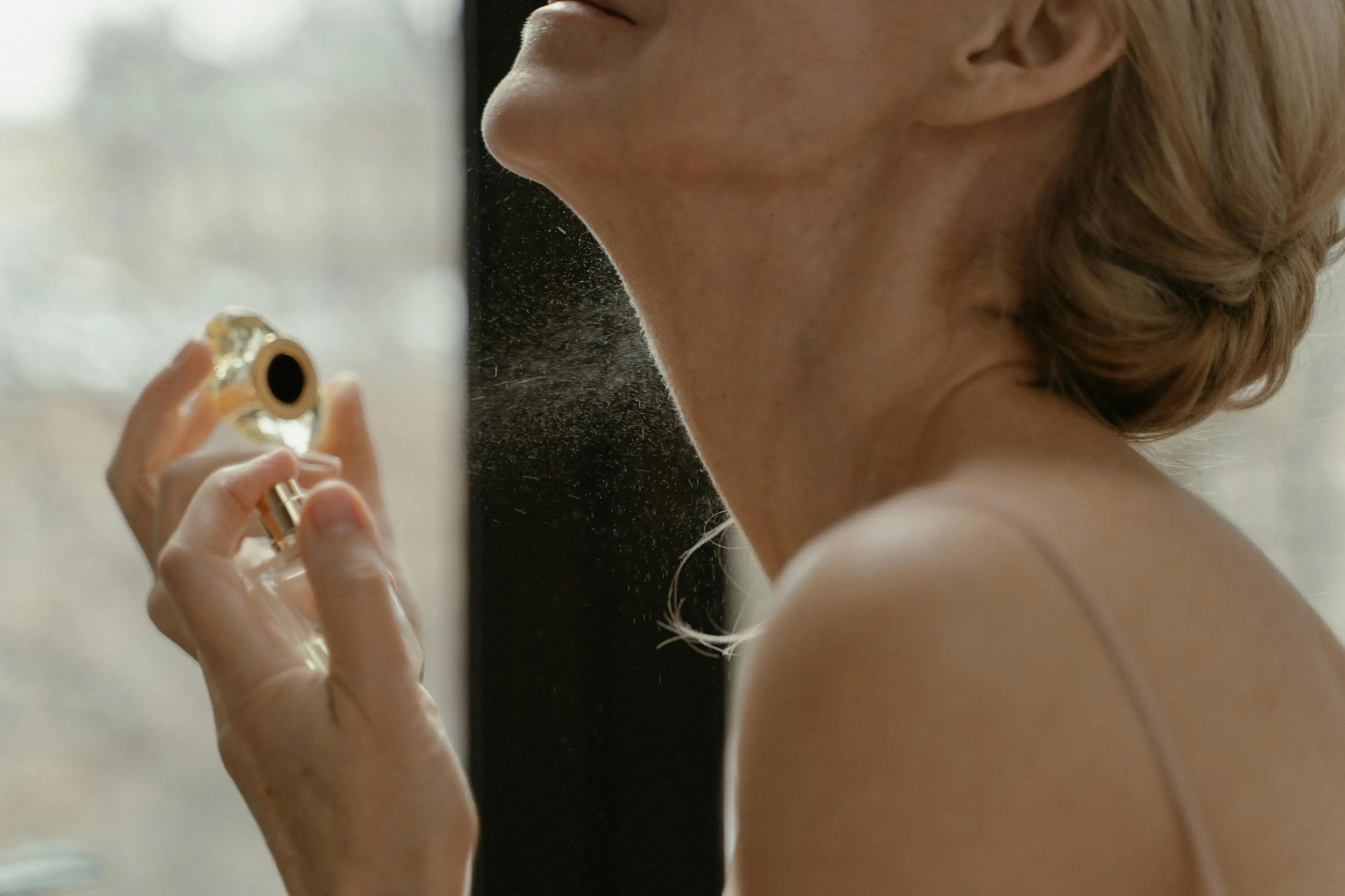 A close-up shot of a person's wrist with a small spray of perfume, illustrating the testing process.